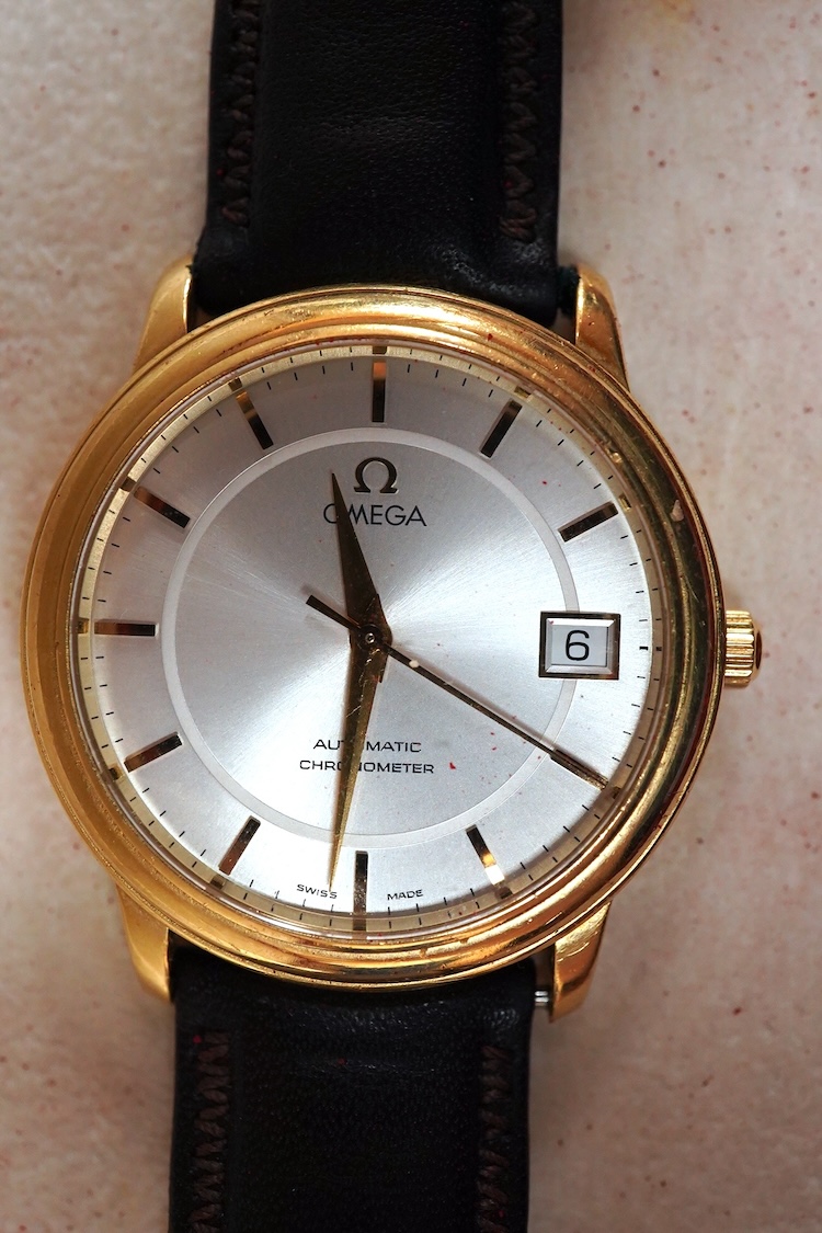 A gentleman's late 1990's 18ct gold Omega Automatic Chronometer wrist watch, with baton numerals and date aperture, case diameter 35mm, on an associated leather stray with plated buckle with Omega insignia, with box and